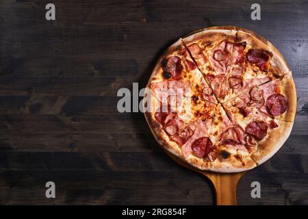 Plan plat d'une pizza fraîchement cuite sur une planche de bois Banque D'Images