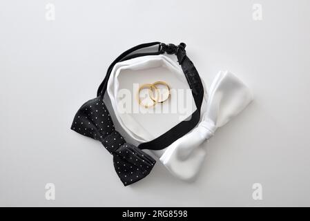 Fond de mariage gay conceptuel avec noeud papillon noir et blanc formant un cercle et des anneaux de mariage au centre. Vue de dessus. Banque D'Images