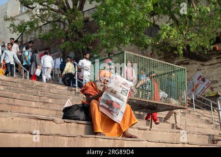 Varanasi Inde - Mars 13 2023 moine lisant le journal sur Dashvamedh Ghat, Varanasi, Inde Banque D'Images