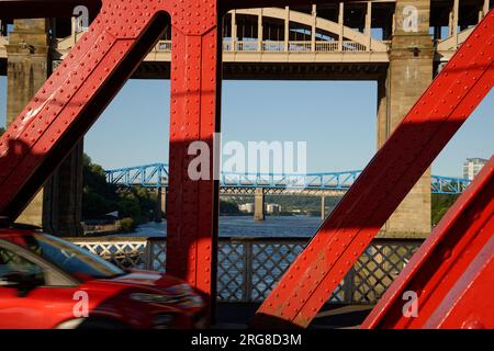 Le pont tournant à Newcastle. Pont routier en métal peint en rouge et blanc sur la rivière Tyne. Le pont de haut niveau en arrière-plan. Banque D'Images