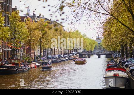 AMSTERDAM, PAYS-BAS - 18 AOÛT 2022 : les gens profitent d'une belle journée de printemps à Amsterdam avec ses canaux, ponts et bateaux Banque D'Images