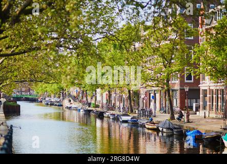 AMSTERDAM, PAYS-BAS - 18 AOÛT 2022 : les gens profitent d'une belle journée de printemps à Amsterdam avec ses canaux, ponts et bateaux Banque D'Images