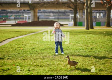 Heureuse petite fille courir et chasser les canards dans le parc André-Citroën de Paris, France Banque D'Images