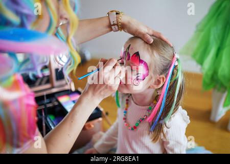 Peinture de visage d'enfants. Artiste peignant petite fille d'enfant d'âge préscolaire comme licorne sur une fête d'anniversaire. Activités créatives pour les enfants Banque D'Images