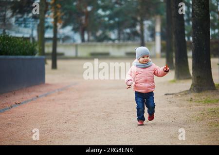 Adorable petite fille marchant dans le parc le jour d'hiver ou de printemps, Paris, France Banque D'Images