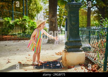 Adorable petite fille jouant avec de l'eau sur une chaude journée d'été. Enfant heureux marchant dans le parc. Activités de plein air pour les enfants Banque D'Images