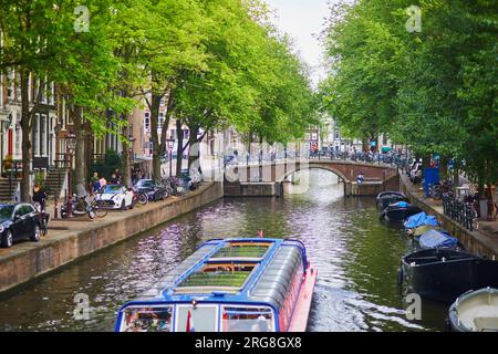 AMSTERDAM, PAYS-BAS - 18 AOÛT 2022 : les gens profitent d'une belle journée de printemps à Amsterdam avec ses canaux, ponts et bateaux Banque D'Images