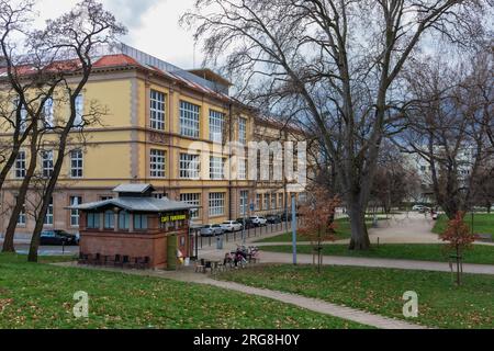 Wroclaw, Pologne - Mars 25 2023 : petite place verte avec petit café et quelques tables et chaises à côté de l'Académie des Beaux-Arts bâtiment Banque D'Images