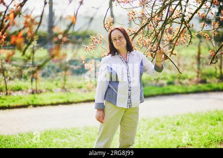 Heureuse femme d'âge moyen appréciant la saison des cerisiers en fleurs un jour de printemps Banque D'Images