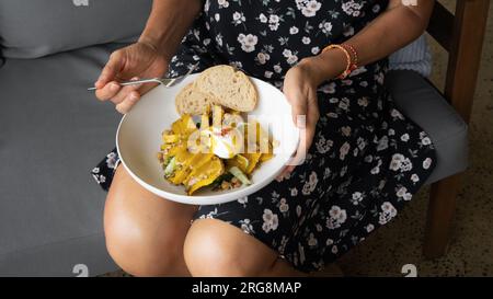 Salade thaïlandaise à la citrouille avec noix et graines. Une femme mange une salade de citrouille tenant une assiette dans ses mains. Banque D'Images