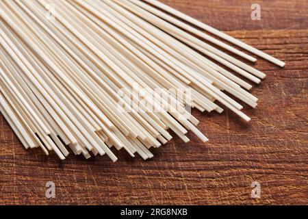 Pile de nouilles udon de blé non cuites sur planche à découper, cuisine orientale et asiatique Banque D'Images