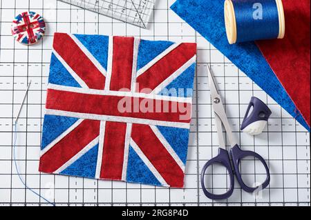 Dessus cousu de coussin comme Union Jack sur tapis d'artisanat blanc, accessoires de couture Banque D'Images