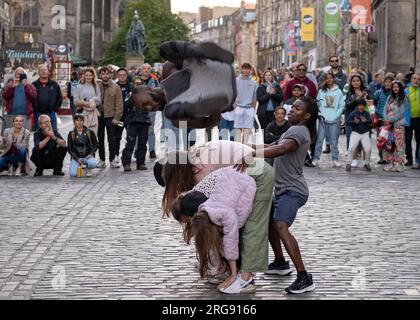 Un membre du groupe guinéen Afrique en Cirque vole dans les airs sur le Royal Mile à Édimbourg pendant le Festival Fringe, août 2023. Écosse. Banque D'Images