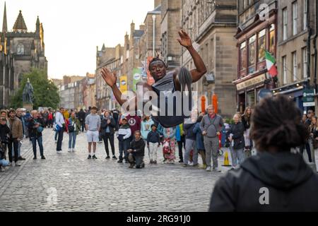 Un membre du groupe guinéen Afrique en Cirque vole dans les airs sur le Royal Mile à Édimbourg pendant le Festival Fringe, août 2023. Écosse. Banque D'Images