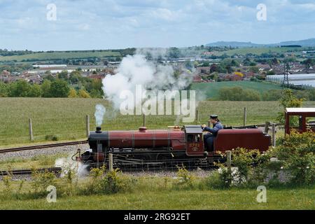 Vue du moteur et du chauffeur du chemin de fer léger Evesham Vale, l'une des attractions familiales du Evesham Country Park, Worcestershire. Ce chemin de fer à vapeur miniature pour passagers a ouvert ses portes en août 2002 avec un écartement étroit de 15 pieds. Banque D'Images