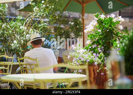 Les gens dégustant des boissons dans un café sur une chaude journée d'été à Gordes, France Banque D'Images