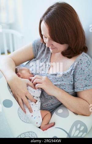 Belle femme avec son adorable bébé fille nouveau-né. Mère et fille ensemble dans la chambre Banque D'Images