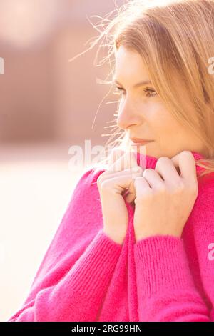 Une vue réconfortante se déploie alors qu'une jeune femme millénaire trouve du réconfort dans son propre cocon de confort. Enveloppée dans un pull rose moelleux, elle ramasse doucement son visage, savourant la chaleur et la douceur qu'il offre. Ce moment tendre dépeint l'essence de l'auto-soin moderne et du contentement, où le simple plaisir d'une étreinte confortable apporte tranquillité et joie. Cozy Millennial Retreat : jeune femme embrassant le confort dans un pull rose moelleux. Photo de haute qualité Banque D'Images
