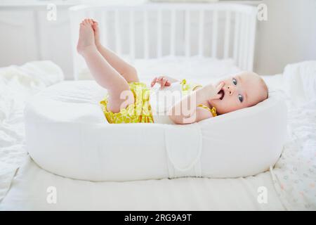 Mignonne petite fille couchée dans le cocon. Enfant heureux en bonne santé dans la pépinière Banque D'Images