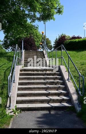 Une double série de marches menant à des balises bélisha à un passage piéton dans un parc de vente au détail. Banque D'Images