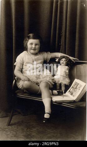 Photographie de studio d'une petite fille photographiée avec une poupée et un livre d'images. Banque D'Images