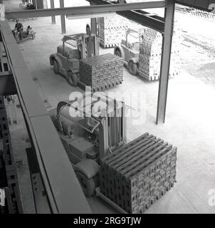 Années 1950, historiques, les travailleurs utilisant des chariots élévateurs déplaçant des piles de briques nouvellement tirées à la London Brick Company à Stewartby, Bedford, Angleterre, à l'époque la plus grande entreprise de fabrication de briques dans le monde. Banque D'Images