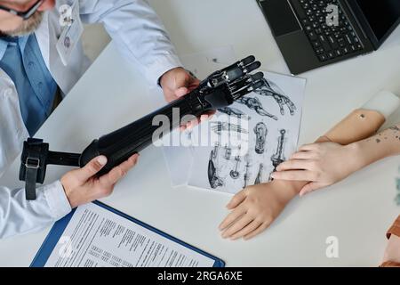 Vue de dessus image de fond d'un médecin méconnaissable démontrant diverses prothèses de bras à la jeune femme Banque D'Images
