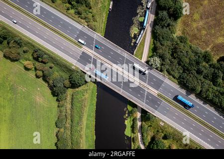 Vue aérienne directement au-dessus d'une autoroute britannique animée passant sur une rivière ou un pont de canal dans la campagne Banque D'Images