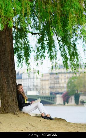 Fille lisant sous un arbre à Paris Banque D'Images