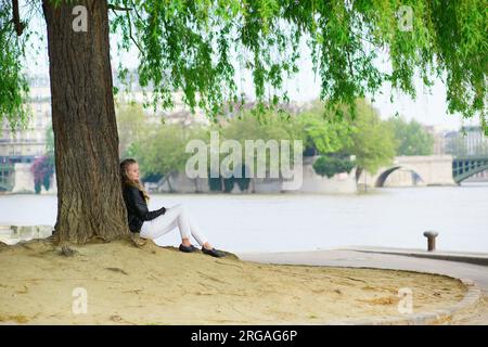 Fille lisant sous un arbre près de Seine Banque D'Images