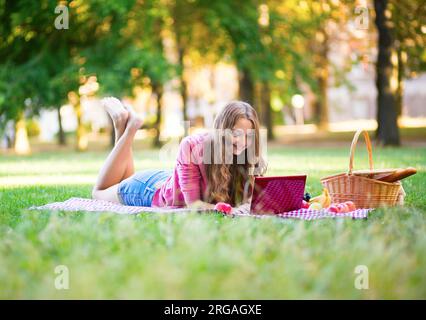 Fille utilisant son ordinateur portable dans le parc Banque D'Images