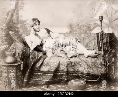 Photographie vintage du XIXe siècle : jeune femme d'Égypte ou de Turquie sur une chaise longue avec un tuyau d'angah. c.1890. Banque D'Images