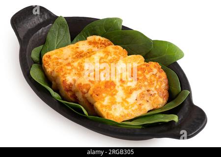 Tranches de fromage halloumi frites avec piment rouge et épinards frais dans un plat en céramique noire isolé sur blanc. Banque D'Images