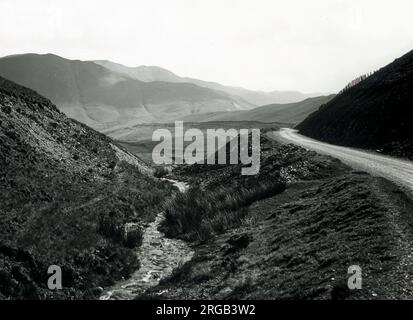 Petit ruisseau et route traversant une vallée dans le parc national de Snowdonia, au nord du pays de Galles. Banque D'Images
