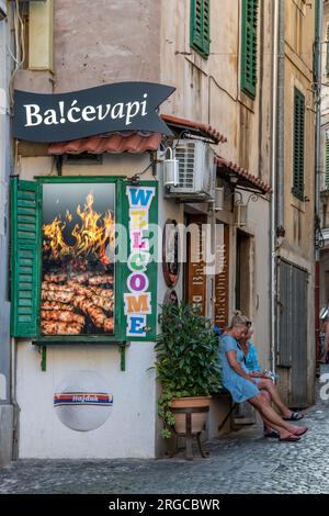 deux dames plus âgées assis sur un banc à l'extérieur d'un petit restaurant ou un café dans la vieille ville de grad divisé en croatie. Banque D'Images