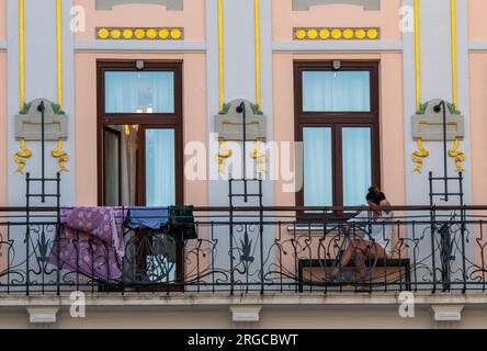 dame âgée assise sur un balcon architectural vintage orné avec portes françaises en grad split croatie. Banque D'Images
