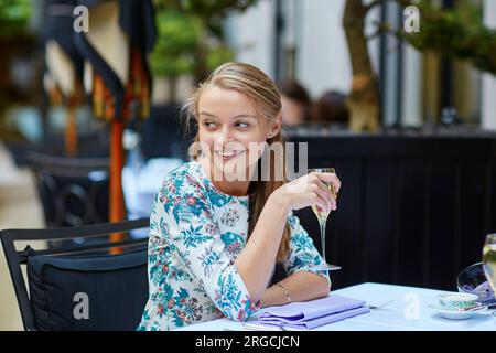 Belle jeune femme dans un restaurant français buvant du champagne Banque D'Images