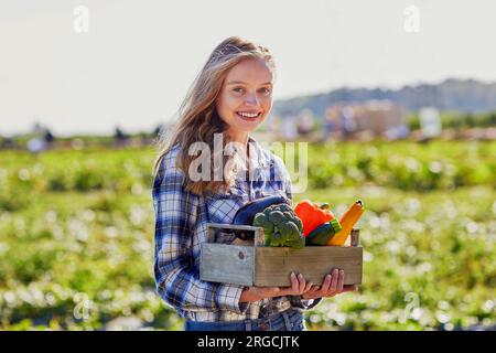 Femme tenant une caisse en bois avec des légumes biologiques frais de la ferme Banque D'Images