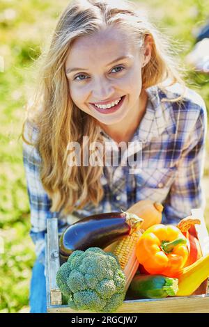 Femme tenant une caisse en bois avec des légumes biologiques frais de la ferme Banque D'Images