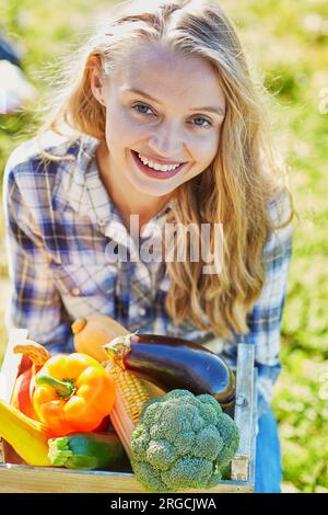 Femme tenant une caisse en bois avec des légumes biologiques frais de la ferme Banque D'Images