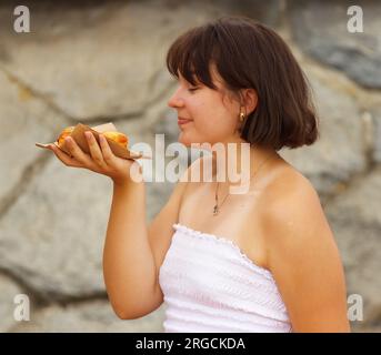 Jolie jeune femme posant avec une pâtisserie achetée sur un stand de marché fermier. Banque D'Images