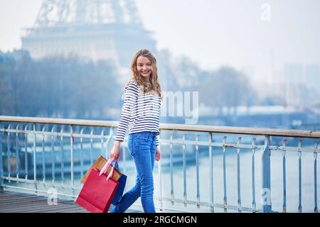 Belle jeune fille avec des sacs à provisions près de la tour Eiffel. Tourisme shopping à Paris concept Banque D'Images