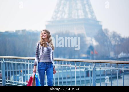 Belle jeune fille avec des sacs à provisions près de la tour Eiffel. Tourisme shopping à Paris concept Banque D'Images