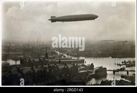 Une superbe carte postale photographique montrant le dirigeable Graf Zeppelin volant au-dessus du Kehrwiederspitze dans le port de Hambourg, en Allemagne. Banque D'Images