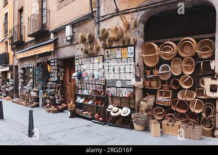 Ségovie, Espagne, 03.10.21. Boutique de souvenirs exposée dans une rue médiévale étroite avec paniers en osier, chapeaux, carreaux décoratifs, aimants, poterie. Banque D'Images