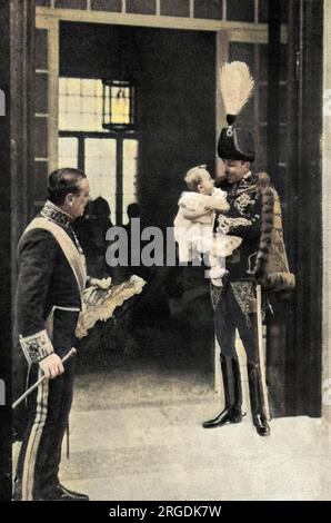 Le roi Alphonse XIII d'Espagne à la Granja, vêtu en uniforme pour le baptême de sa nouvelle fille, profite d'un moment intime avec son deuxième fils, Infant Jaime. Banque D'Images