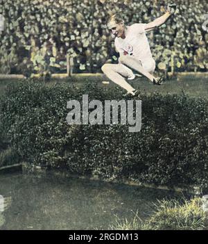 Lord Burghley, médaillé d'or de 400 mètres haies, au saut d'eau dans la steeplechase lors d'une rencontre d'athlétisme au pont Stamford, peu après sa victoire aux Jeux Olympiques d'Amsterdam en 1928. David George Brownlow Cecil, 6th marquis d'Exeter (1905 - 1981), Lord Burghley était un athlète, un responsable sportif et un politicien conservateur en tant qu'athlète, Burghley était un très ferrant praticien qui a placé des boîtes d'allumettes sur des haies et s'est entraîné à frapper les boîtes d'allumettes avec son pied principal sans toucher l'obstacle. En 1927, sa dernière année au Magdalene College de Cambridge, il a surpris ses collègues par les Banque D'Images