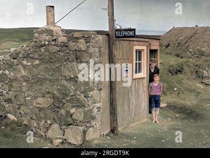 Un homme et un garçon se tiennent à la porte du bureau de poste rustique de Timsgarry, à Uig, à l'île de Lewis, dans les Hébrides extérieures, en Écosse. Banque D'Images