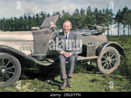 Un homme assis sur la planche à pied d'une voiture de sport. Banque D'Images