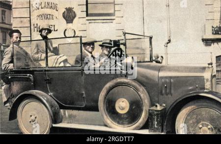 Quatre personnes dans une voiture à toit ouvert dans une station balnéaire. Banque D'Images